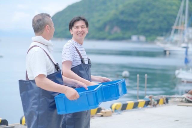 トロ箱を運ぶ２人の漁師の男性
